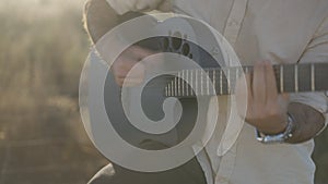 Man's Hands Playing on Black Acoustic Ovation Guitar Outdoors at Sunset - close-up, slow-motion