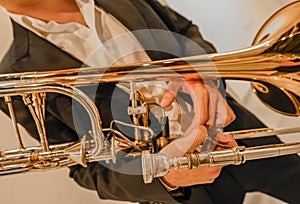 Man's hands playing the trombone in the orchestra.