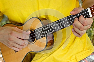 Man's hands playing ukulele
