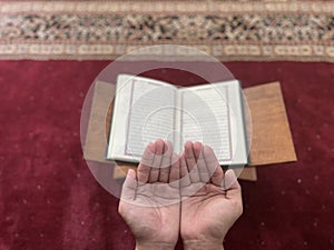 A man\'s hands praying against the background of a newspaper and a red carpet