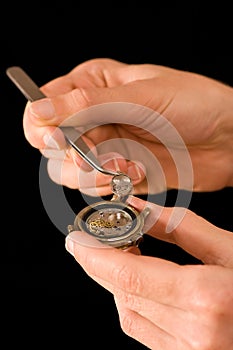 Man's hands repairing old watch, holding a part