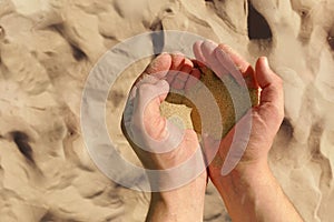 Man`s hands with sand, man holds sand. Golden sand on the background. The concept of hope for better future, kindness and faith in