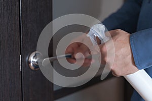 Man`s hands with a sanitizer disinfects doorknobs photo