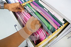 Man`s hands Search files document of hanging file folders in drawer in a whole pile of full papers