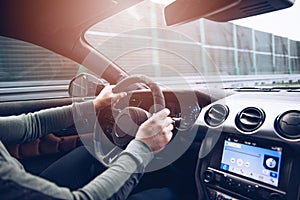 Man`s hands on the steering wheel of a moving car