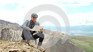 Man's hands touching screen of digital tablet on the background of mountains