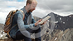 Man's hands touching screen of digital tablet on the background of mountains