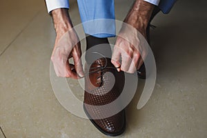 Man`s hands tying shoelace of his new shoes. People, business, fashion and footwear concept - close up of man leg and