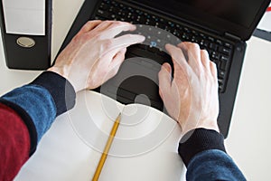 Man`s hands typing on laptop key