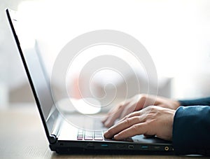 Man`s hands typing on a laptop keyboard.