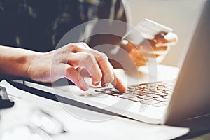 Man`s hands typing laptop keyboard and holding credit card onlin