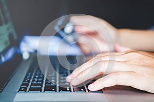 Man`s hands typing laptop keyboard and holding credit card onlin