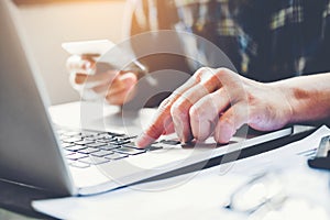 Man`s hands typing laptop keyboard and holding credit card onlin