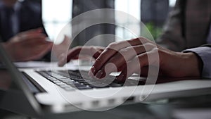 Man's hands typing on laptop keyboard in interior