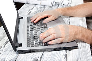 Man's hands typing laptop keyboard making online payment at home against the wooden table. On-line shopping concept