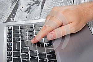 Man's hands typing laptop keyboard making online payment at home against the wooden table. On-line shopping concept