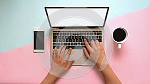 Man`s hands typing mockup laptop computer with smartphone and laptop on pastel desk.