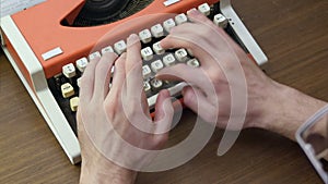Man`s hands typing on an old red mechanical typewriter