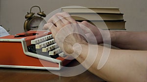 Man`s hands typing on a red retro typewriter