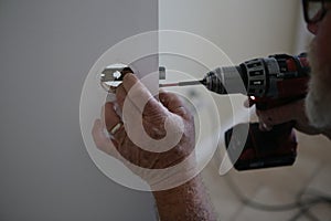 Man`s hands using drill to repair door knob