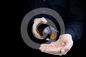 The man`s hands, in which there is a jar of omega 3 capsules, he pours them into the palm of his hand fish oil