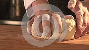 Man`s hands working the dough on table covered with flour. Slowmotion. Close-up