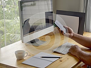 man& x27;s holding phone on desk at home