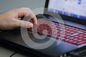 Man& x27;s left hand on the illuminated laptop keyboard