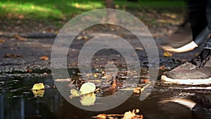 Man s Leg in a Crossbar Enters a Dirty Puddle with Autumn Leaves