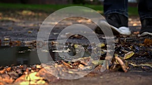 Man s Leg in a Crossbar Enters a Dirty Puddle with Autumn Leaves