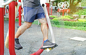 Man`s legs muscle while doing exercise at outdoor fitness equipment in the park, concept health care in elderly people, lifestyle