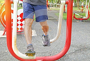 Man`s legs muscle while doing exercise at outdoor fitness equipment in the park, concept health care in elderly people, lifestyle