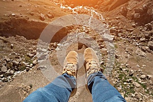 Man's legs over a cliff and a mountain river