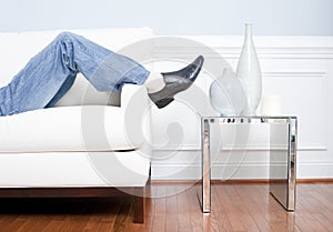 Man's Legs Reclining on White Couch