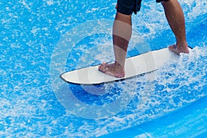 Man`s legs standing on surfboard