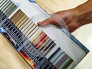 Man`s male hand holding a color palette sample of different colors for customers to chose from while renovating or redesigning