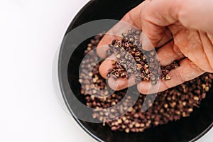Man`s palm taking a scented Sichuan pepper from the bowl on the white table. Sichuan pepper or Chinese pepper or Timur or Nepali