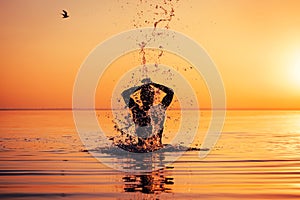 Man`s silhouette in calm water at sunset