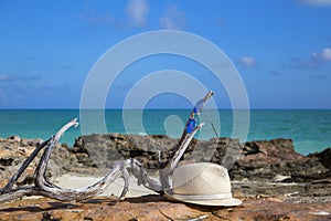 A man`s straw hat and sunglasses lie against the beautiful sea.
