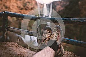 ManÂ´s trekking shoes in a nature of Morocco - Ouzod falls. Close up of hiking boots against waterfall.