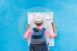 man with a sad travel hat and backpack, looking at a map, in fro