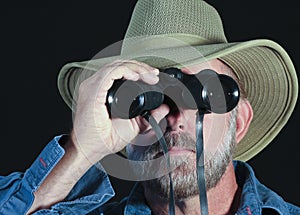 A Man in a Safari Hat Looks Through Binoculars