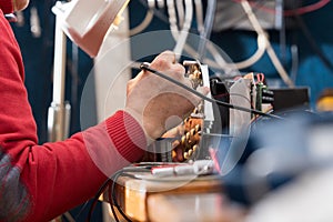 Man with safety glasses repairing motheboard with soldering iron