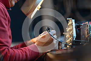 Man with safety glasses repairing motheboard with soldering iron