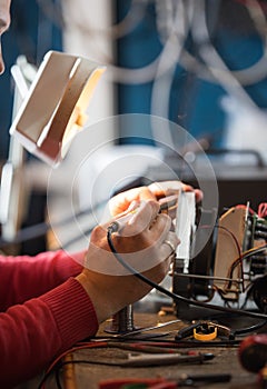 Man with safety glasses repairing motheboard with soldering iron