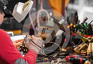 Man with safety glasses repairing motheboard with soldering iron