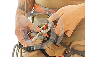 Man in safety harness attaches a figure of eight device to carabiner. photo