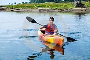 Man With Safety Vest Kayaking Alone on a Calm River