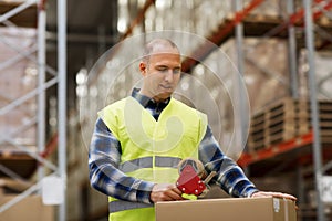 Man in safety vest packing box at warehouse
