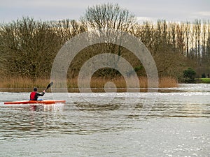 Man in safety vest roving in canoe.